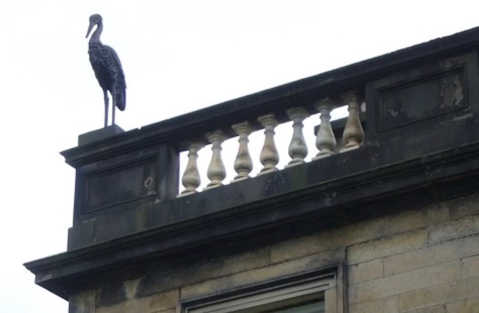 A stone stork (or heron) perched at the end of the Albert Terrace block